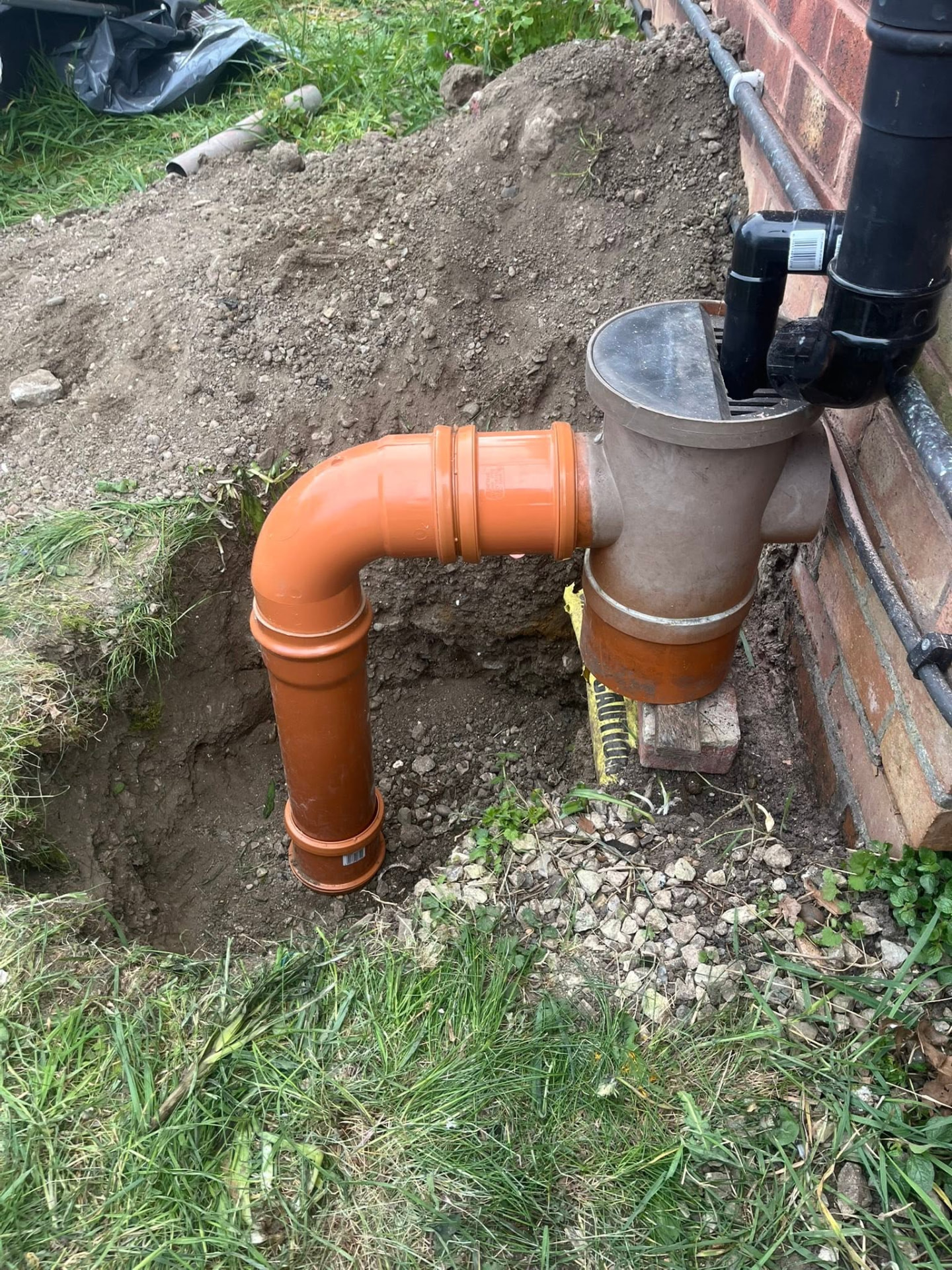 Excavated ground showing new orange underground drainage pipework and gully connected to the soil stack