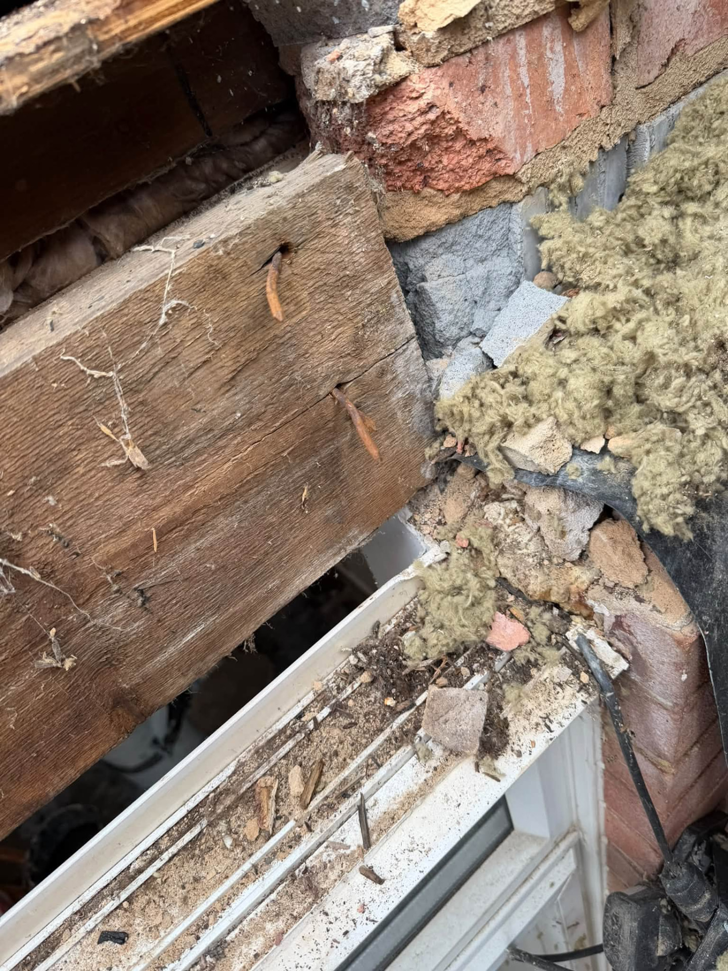 Close-up of rotten timber lintel and damaged brickwork above a window