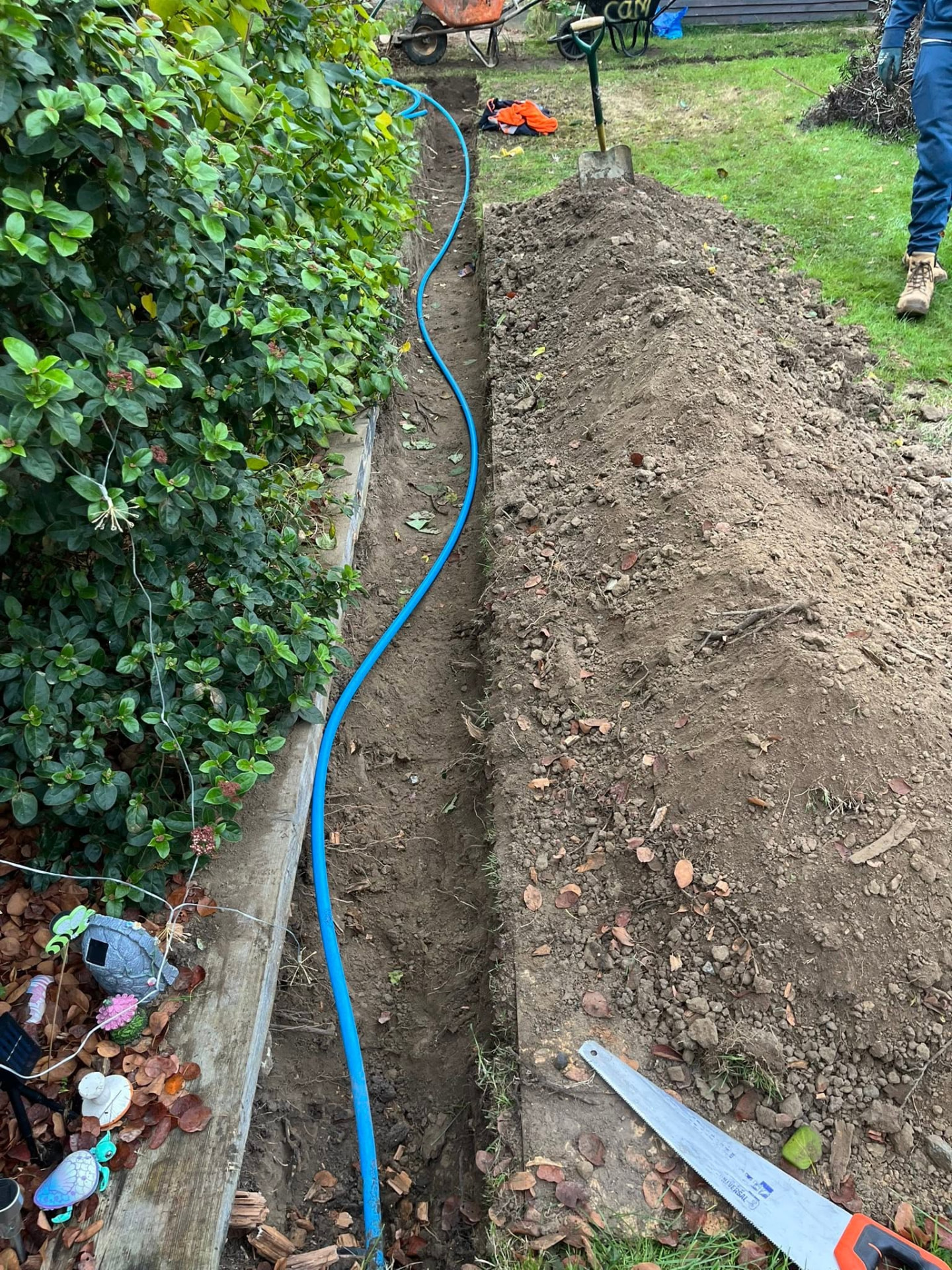 Blue mains water supply pipe laid alongside a freshly dug trench