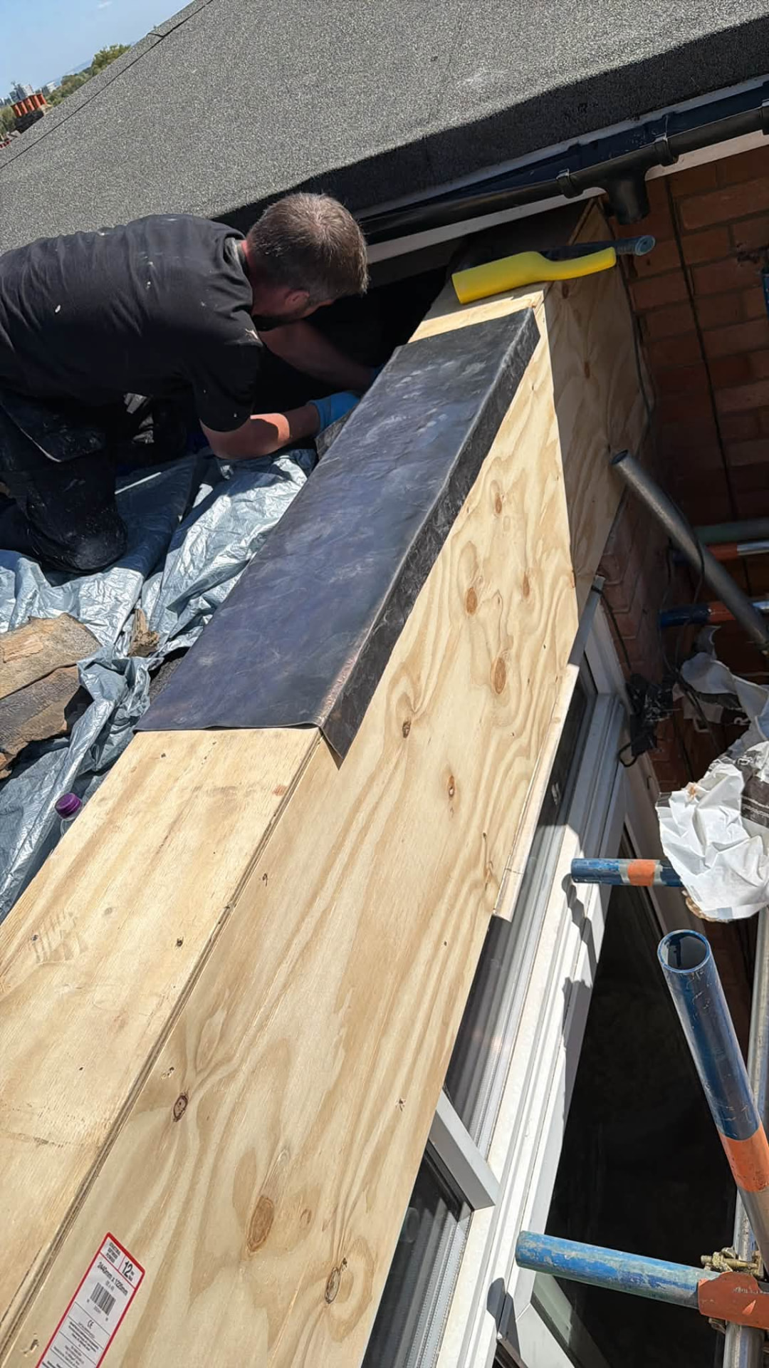 Tradesman dressing new leadwork over the plywood roof edge