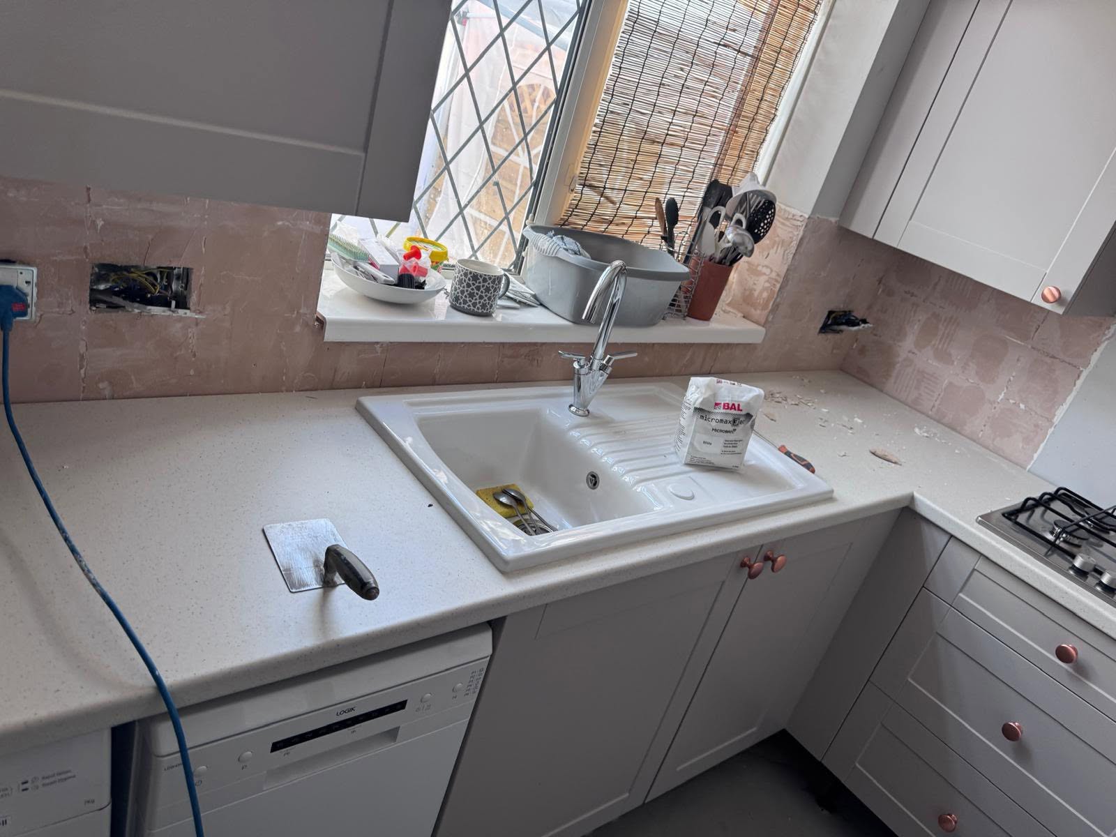 Kitchen sink run with untiled pink plaster splashback area