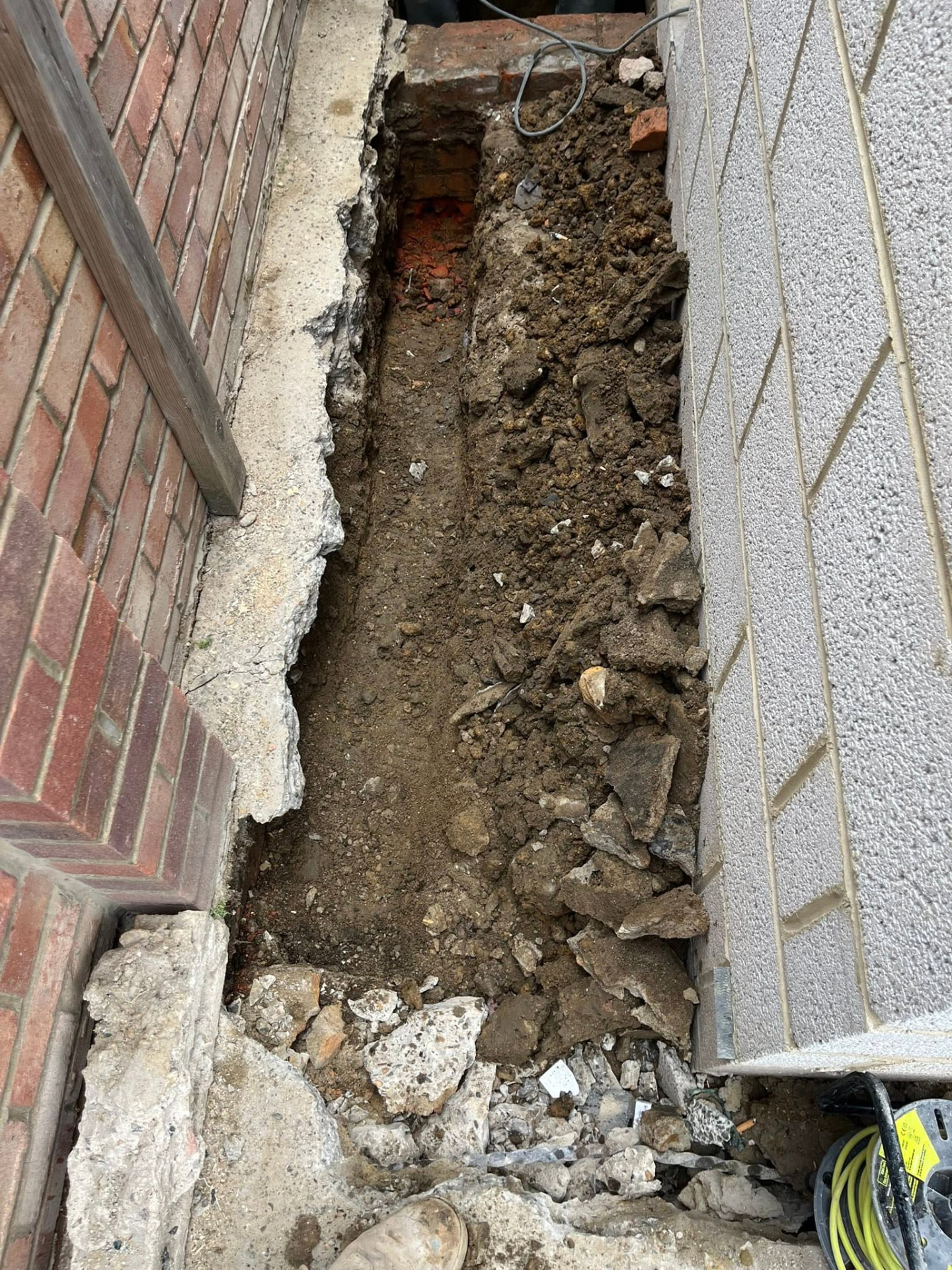 Trench excavated to depth along the wall ready for the new pipe run