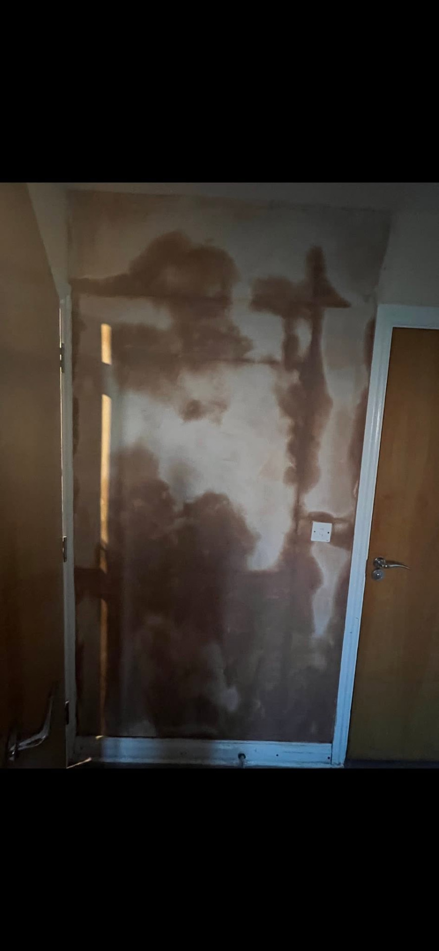Damp-damaged wall with stained, patchy plaster before restoration