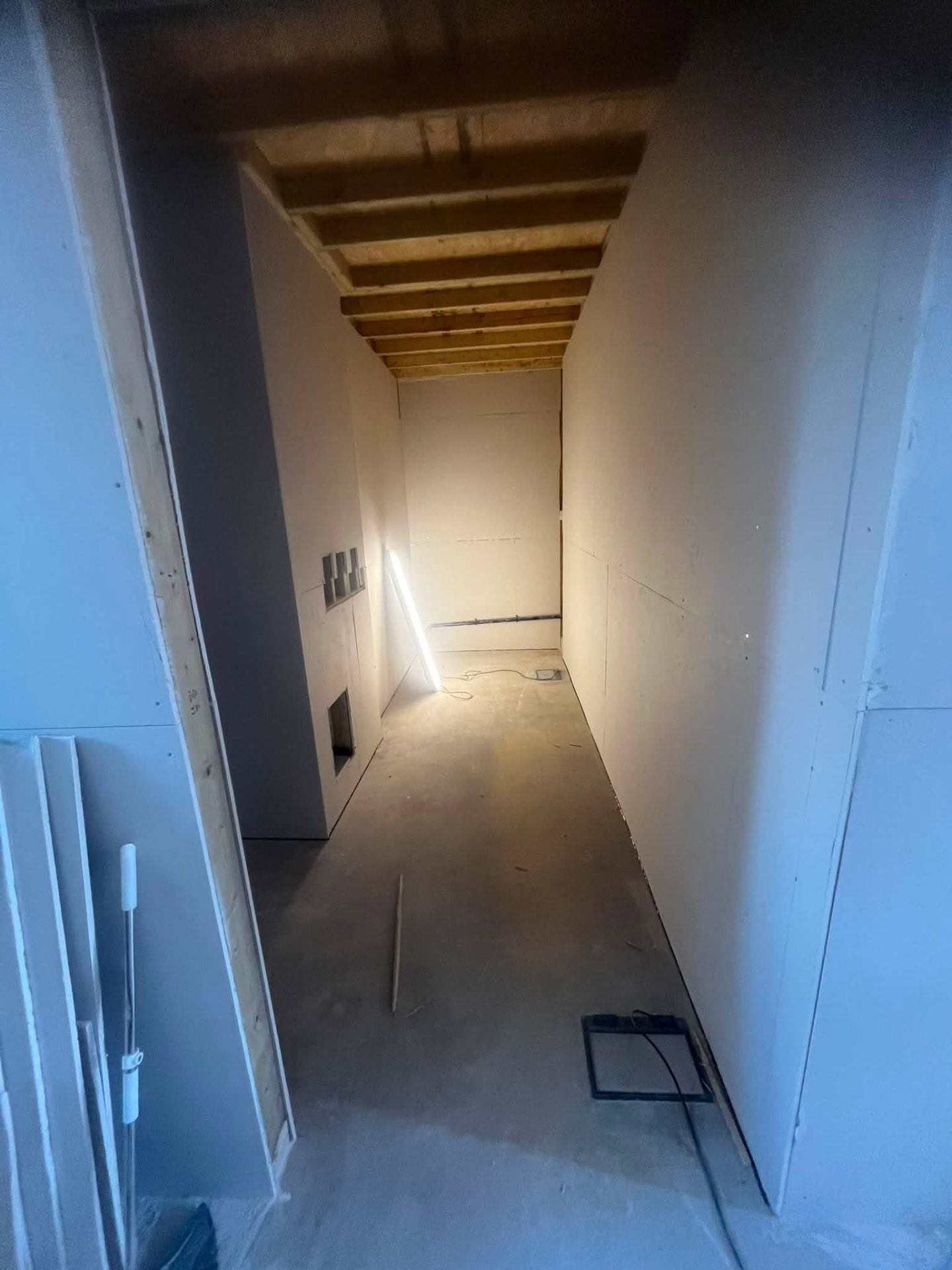 Finished boarded corridor with clean plasterboard walls and exposed joists