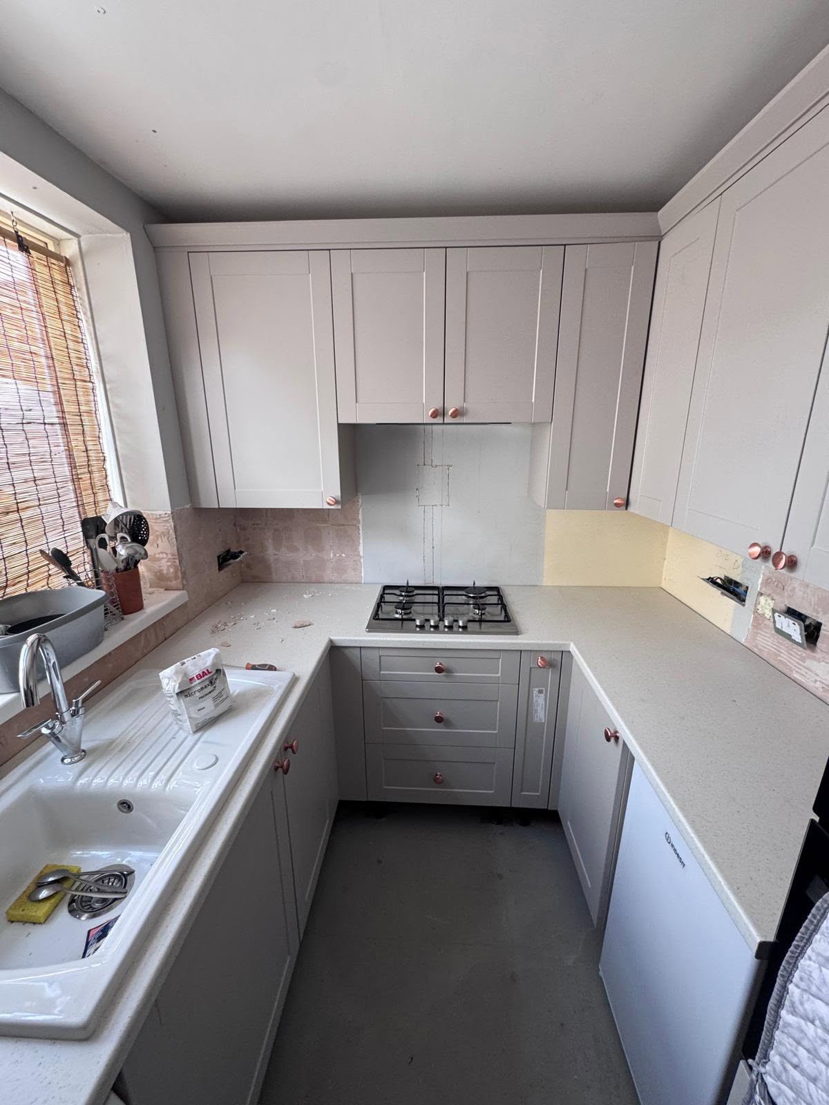 Grey kitchen units with bare walls ready for the new splashback