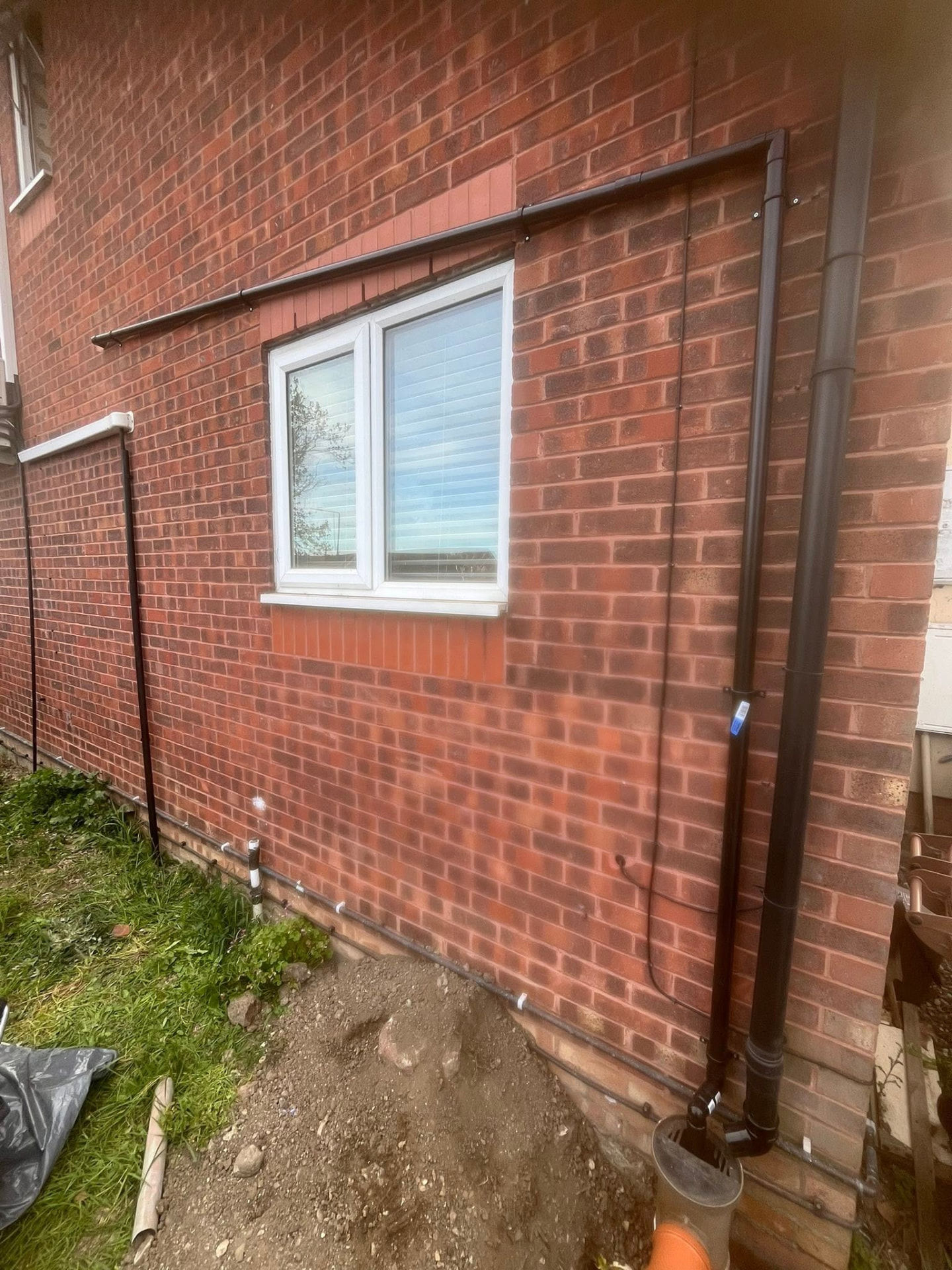 Completed external soil pipe and guttering neatly fitted to the brick wall with ground reinstated