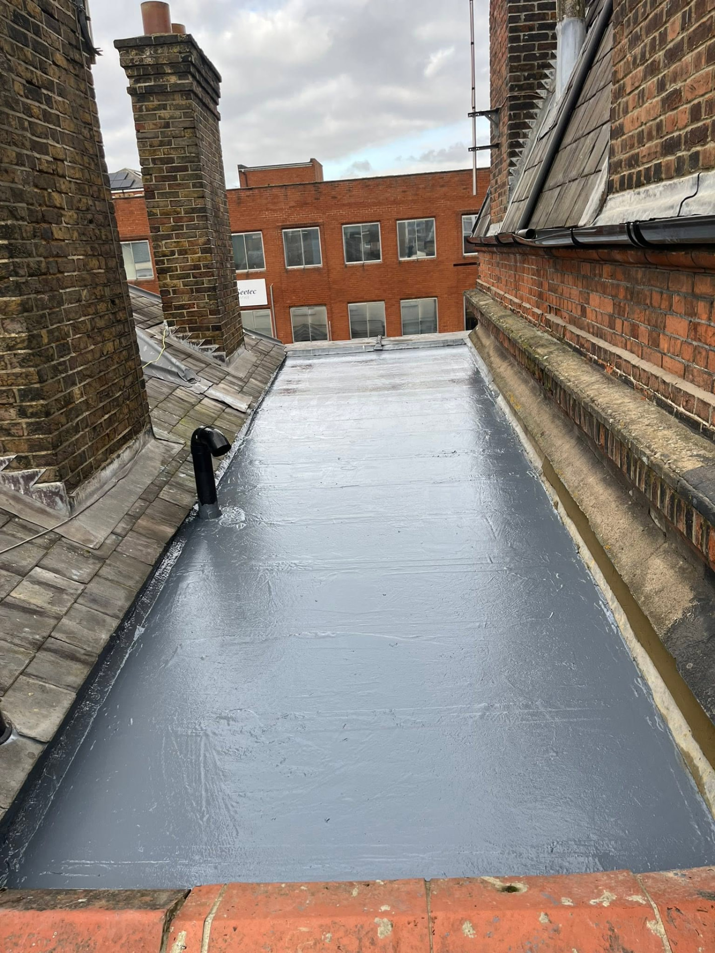 Newly completed flat roof with liquid rubber waterproof coating between brick walls