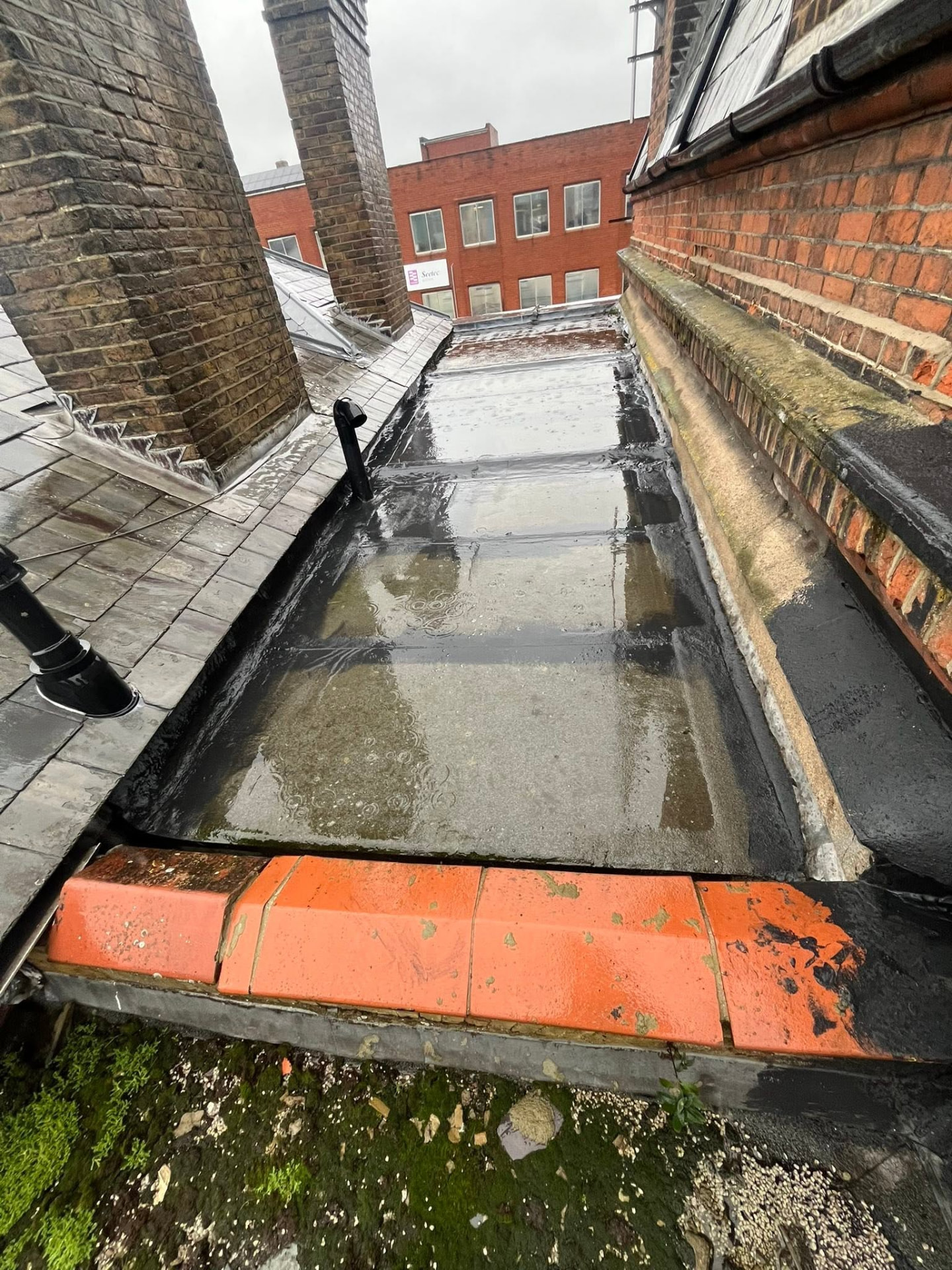 Worn-out felt flat roof holding standing water after rain