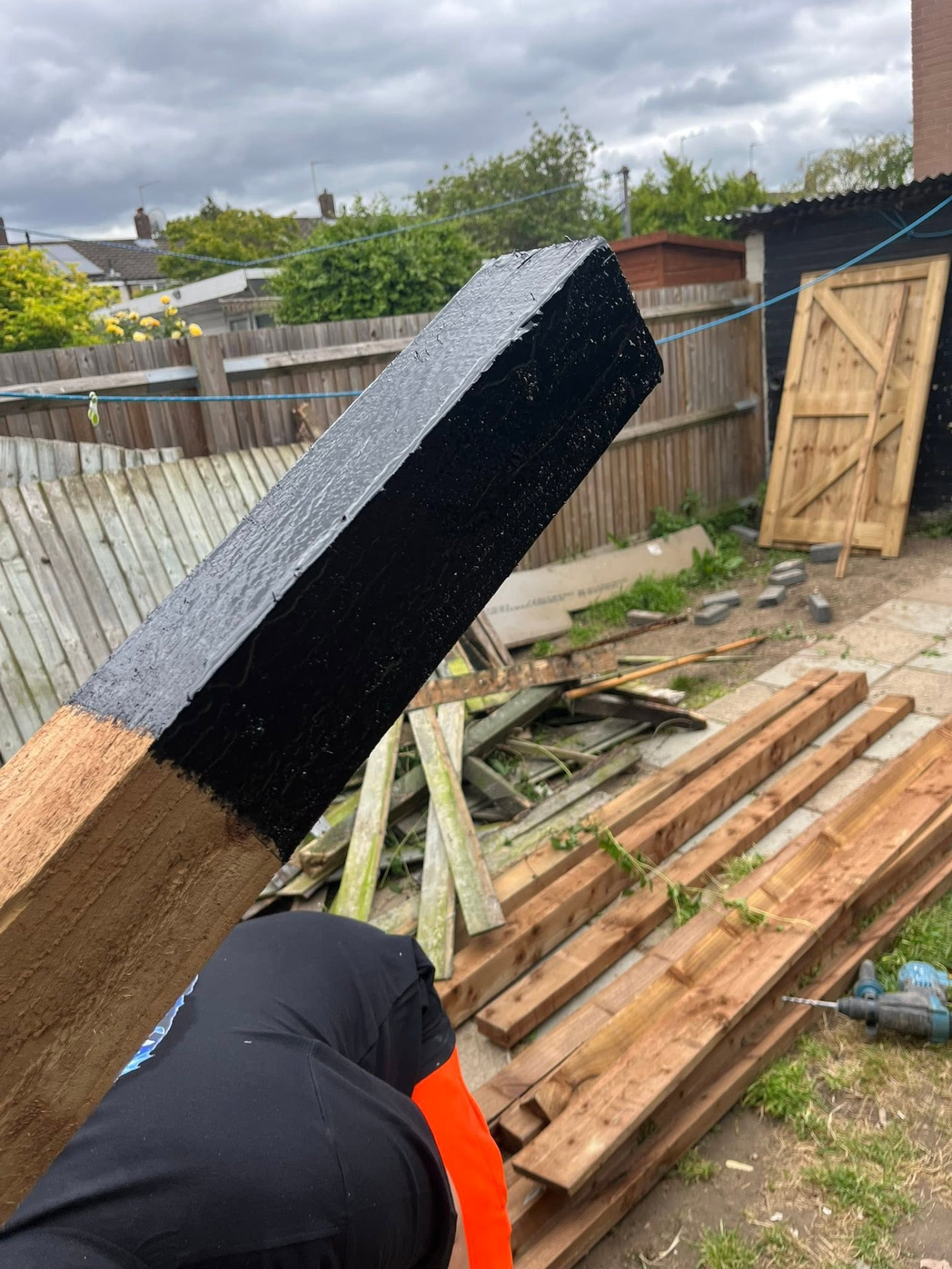 Timber post treated with protective bitumen paint before going below ground