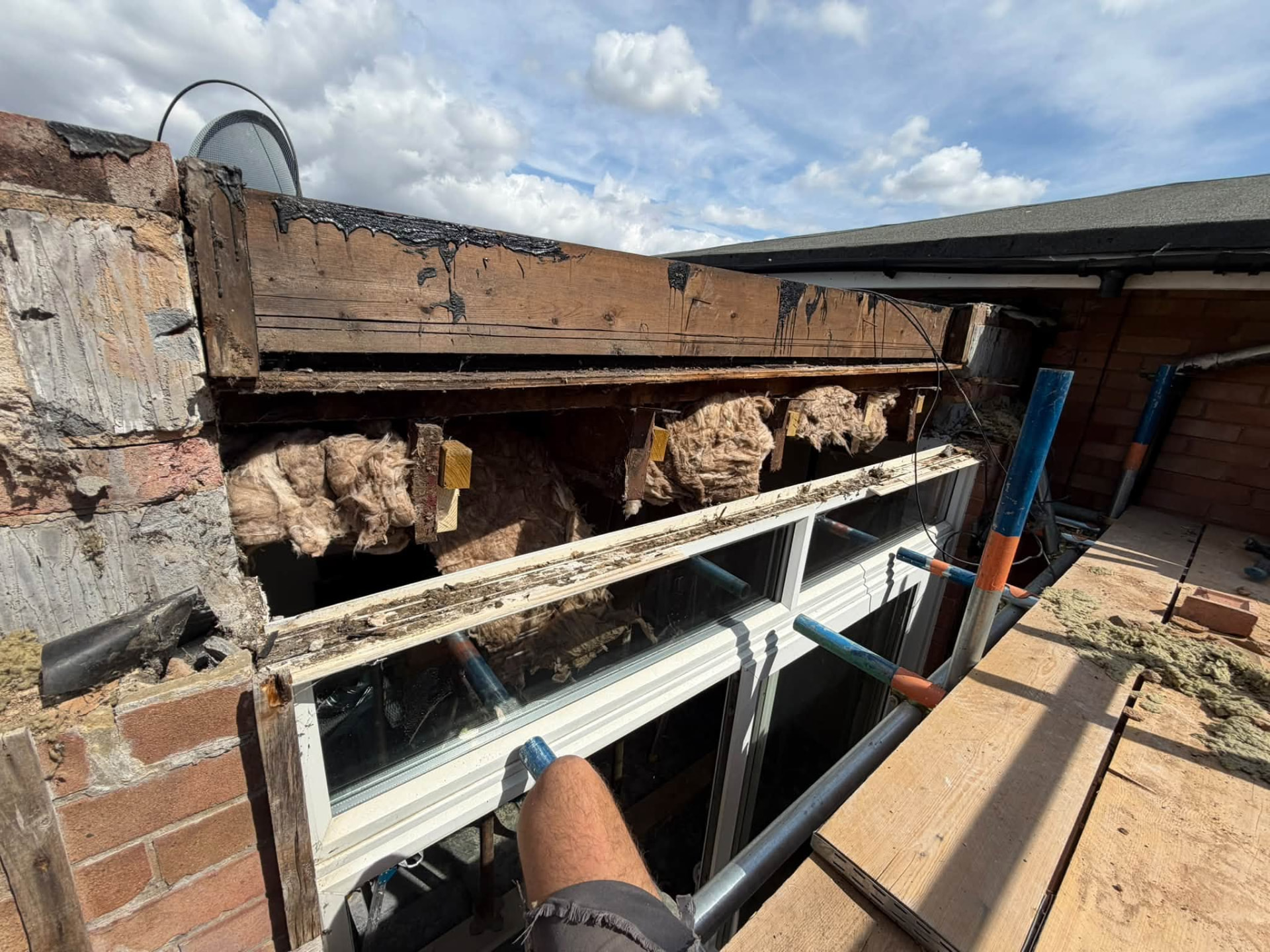 Roof level view of exposed rafters and insulation during structural repairs