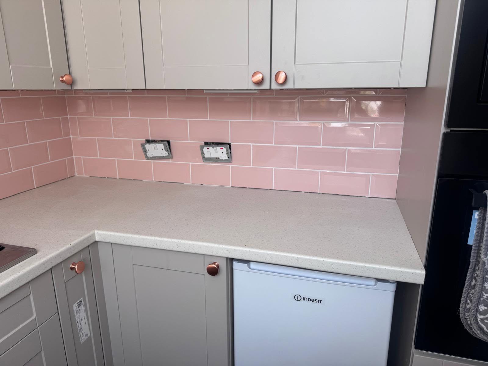 Glossy pink metro tiles finished around the sockets