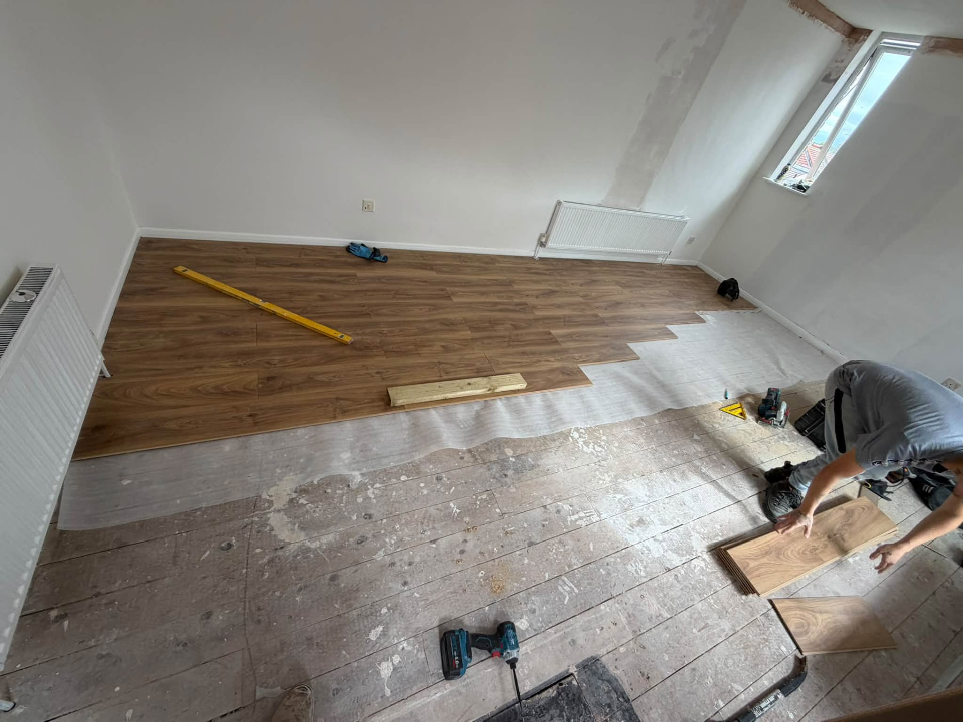 New wood-effect laminate flooring being laid across the prepared subfloor
