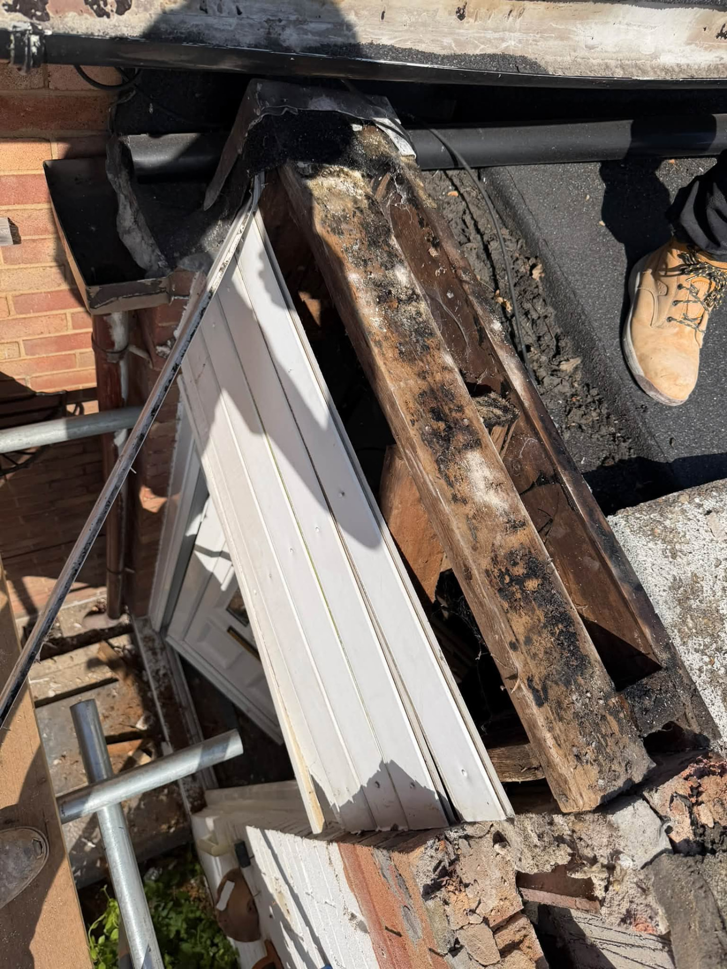 Close-up of charred and damaged timber rafter at the roof edge
