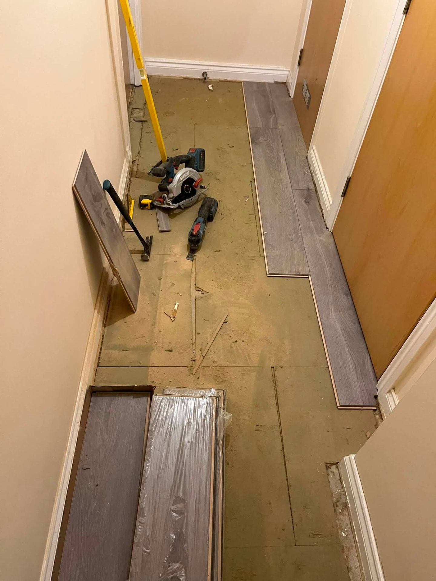 New grey oak laminate boards being cut and laid in the hallway