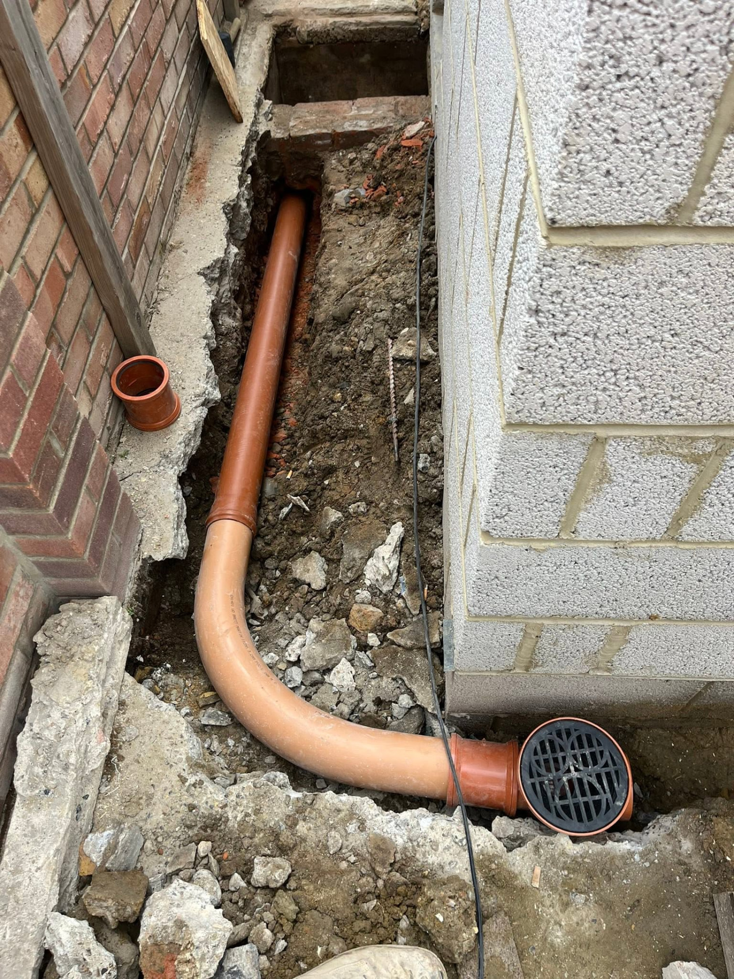 New 4-inch orange pipe laid in the trench with a gully fitted for rainwater