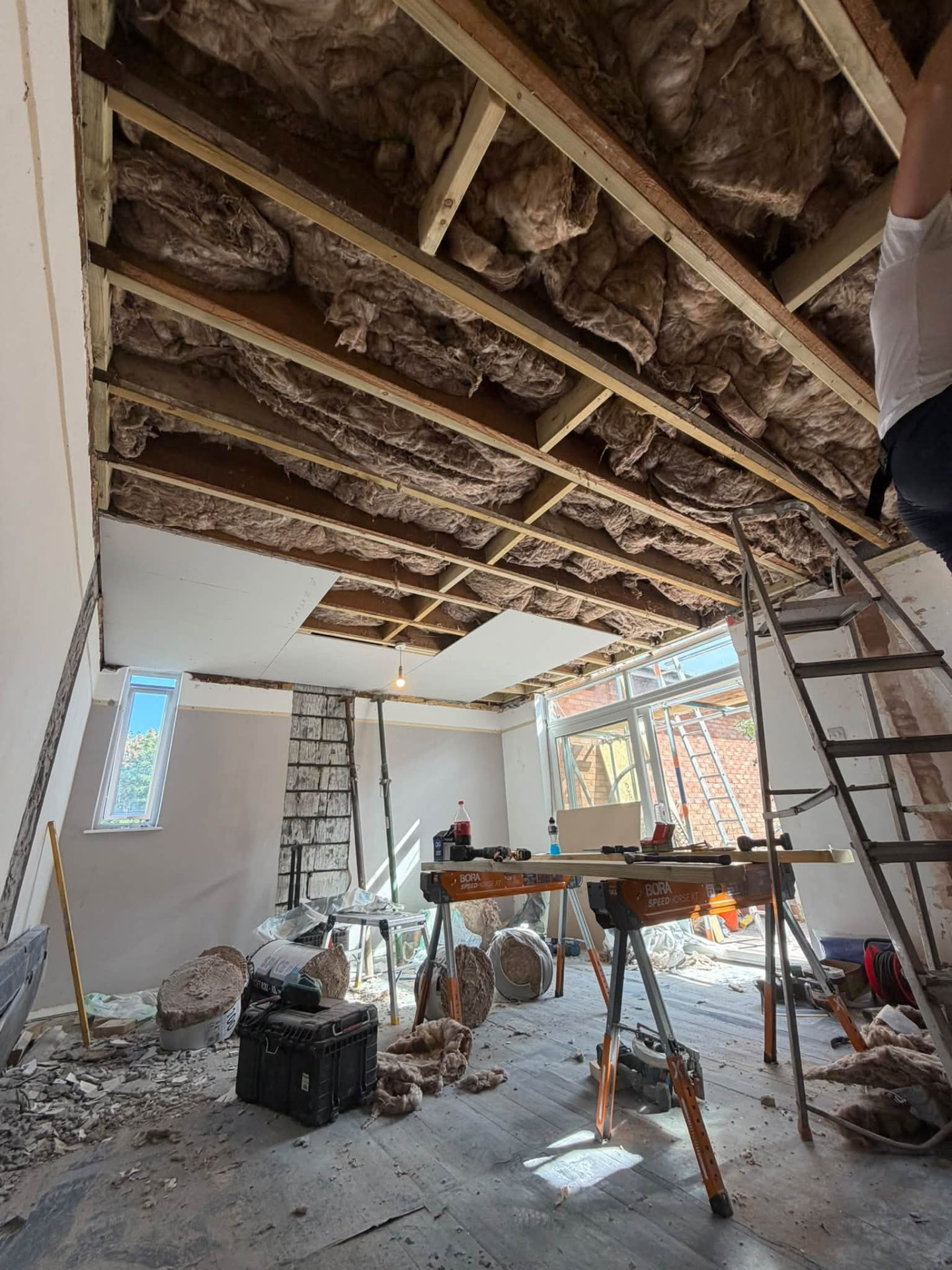 Room with exposed ceiling joists and insulation during the structural repair phase