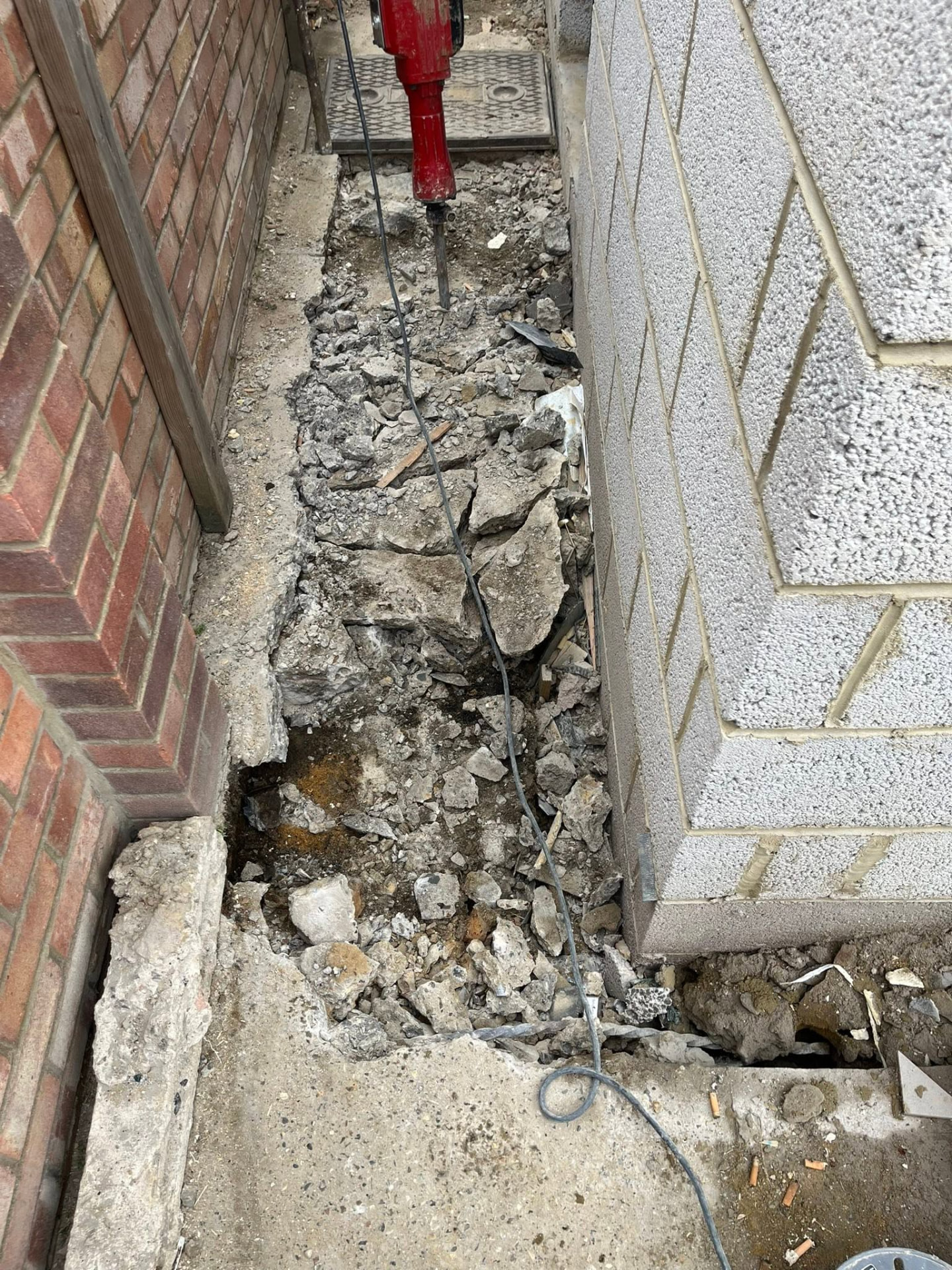 Breaker cutting through the old concrete path to open up the drainage route