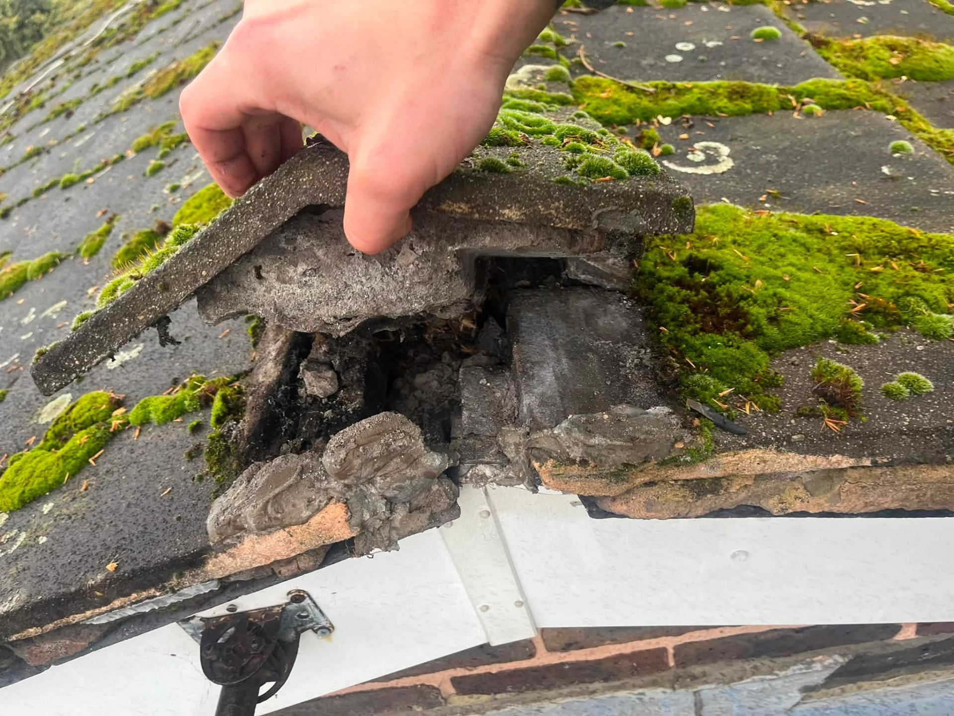Damaged roof tile lifted to inspect the deteriorated bedding beneath