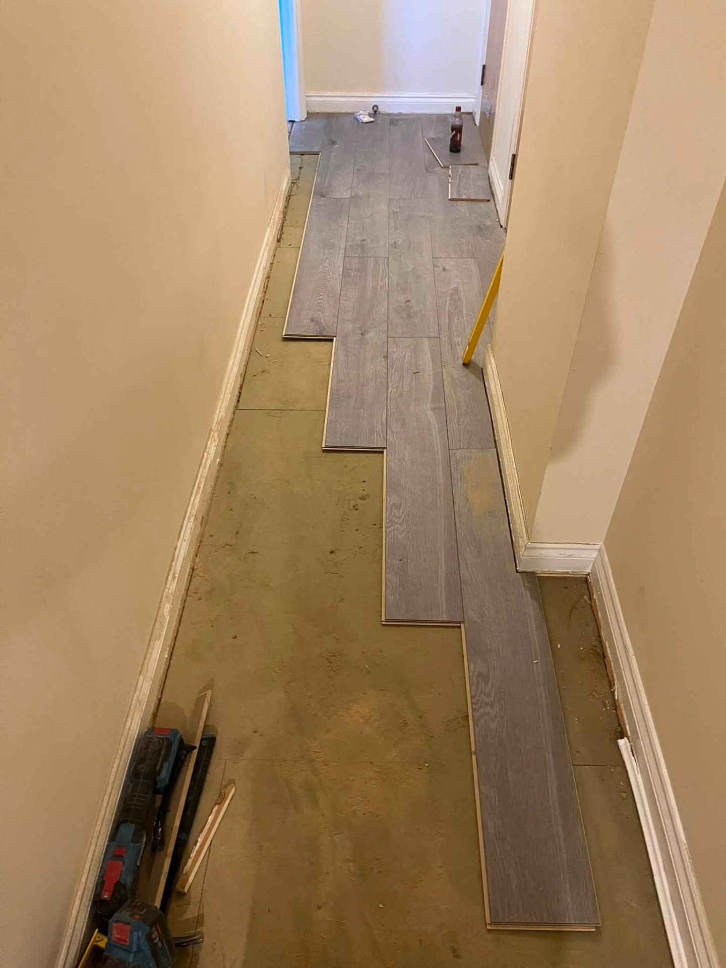 Laminate planks being staggered along the hallway over the new underlay