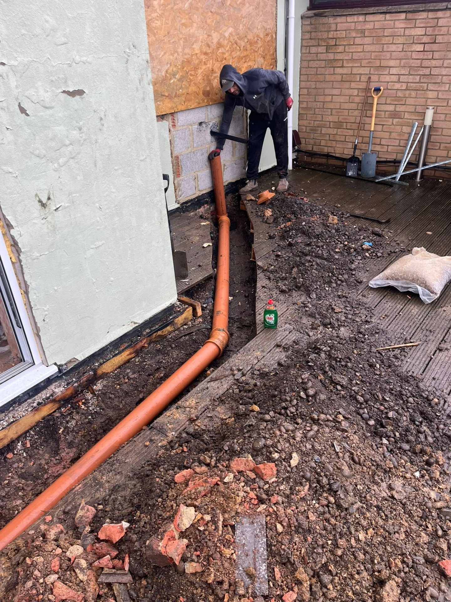 Tradesman fitting the new 4-inch drainage pipe against the blockwork