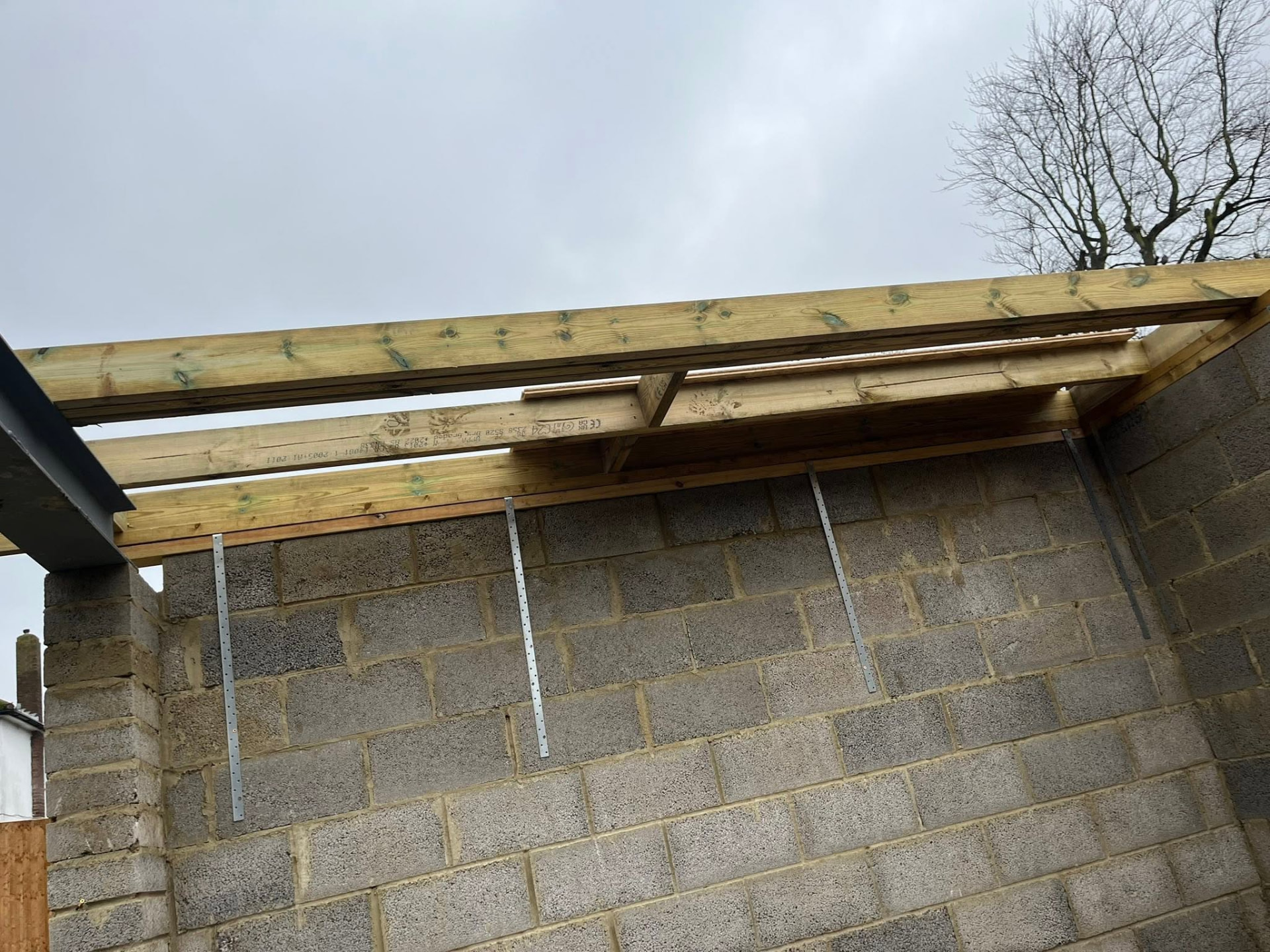 Timber roof beams set out over the new blockwork walls