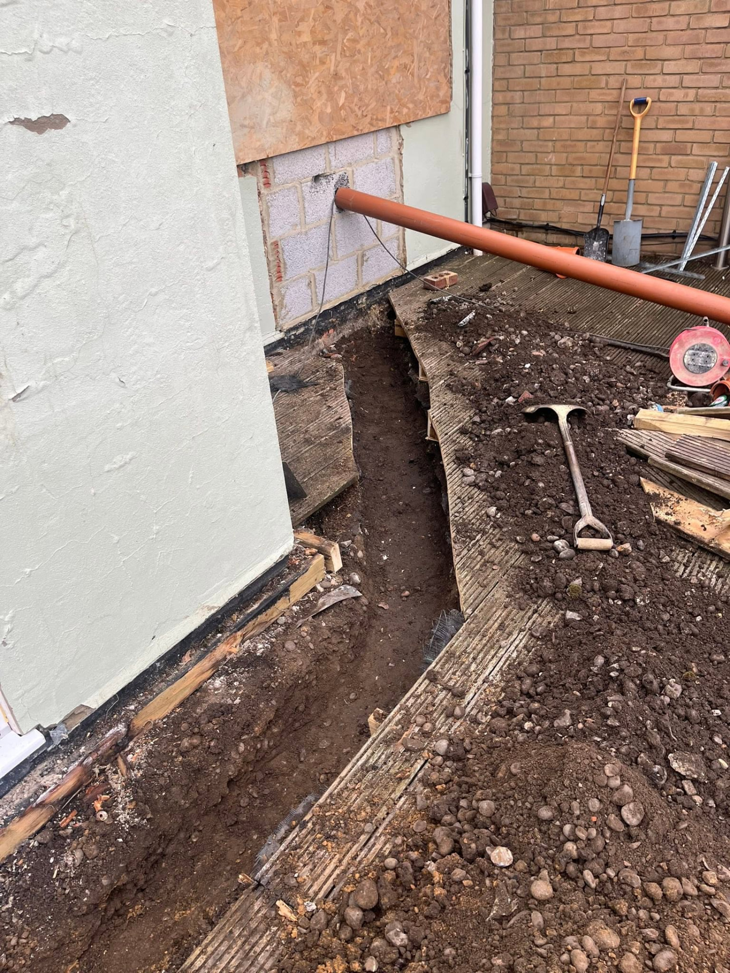 New 4-inch pipe passing through the blocked-up opening into the trench