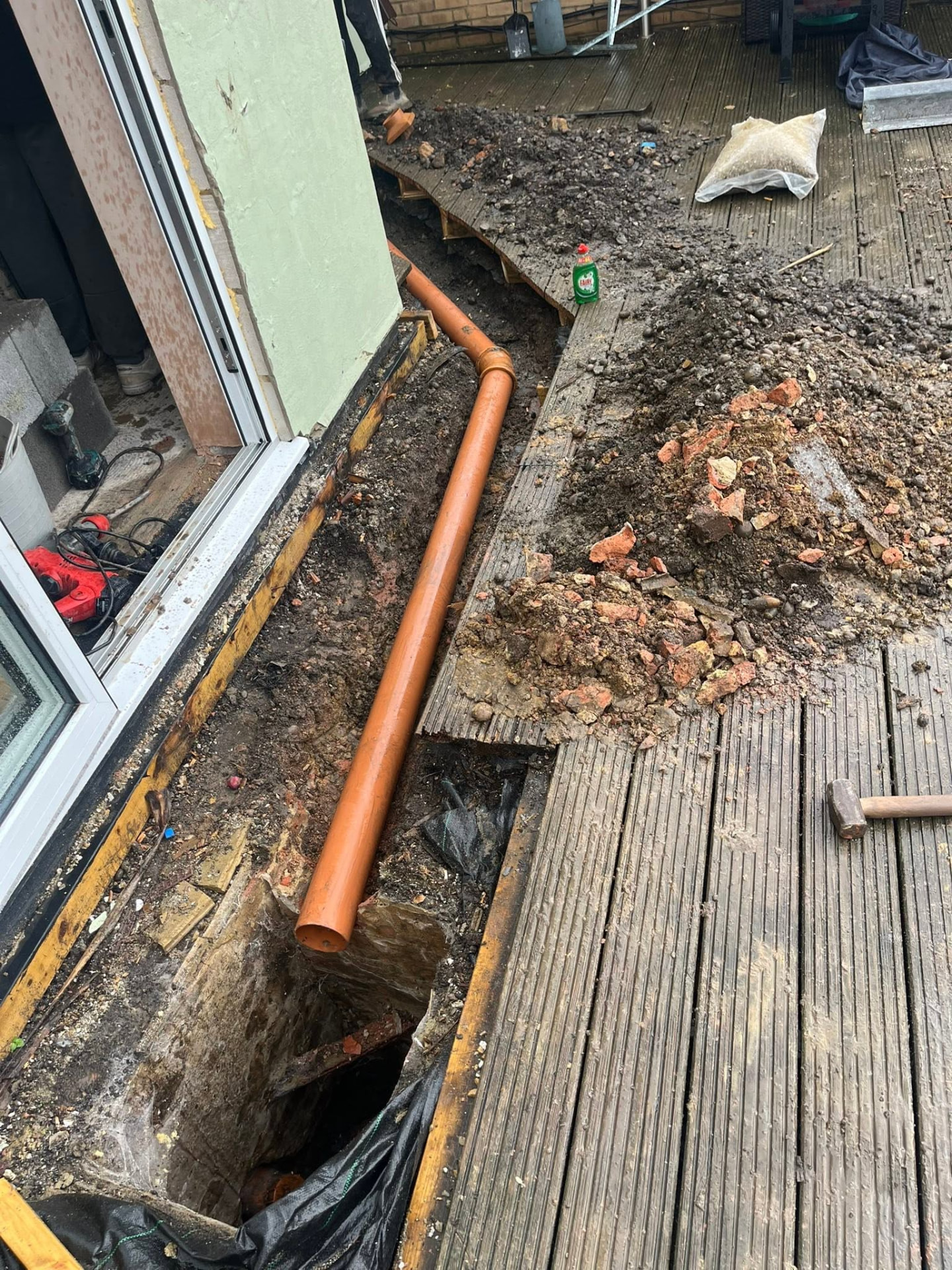 Orange 4-inch drainage run laid along the trench into the existing chamber