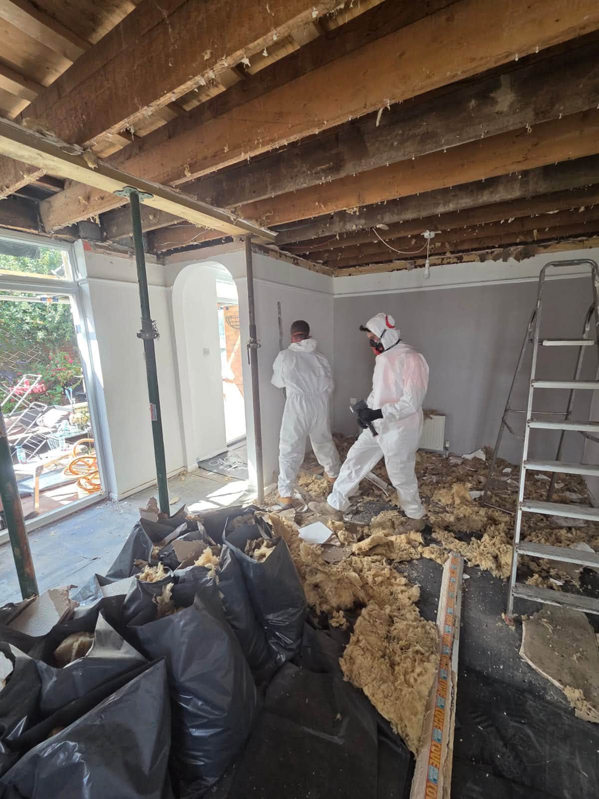 Tradesmen clearing insulation and debris during the full refurbishment