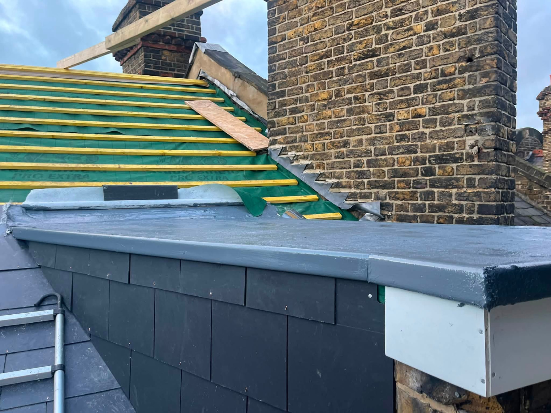 Prepared roof deck with new battens and grey liquid rubber coating applied to the flat section