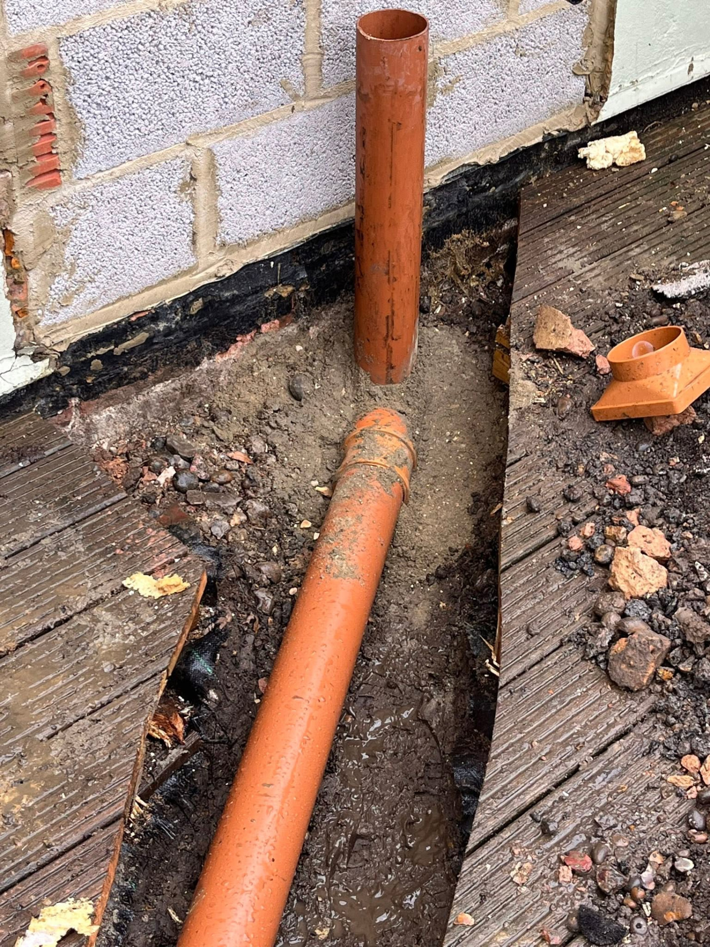 Close-up of the new 4-inch drain connection and vertical stub bedded in sand