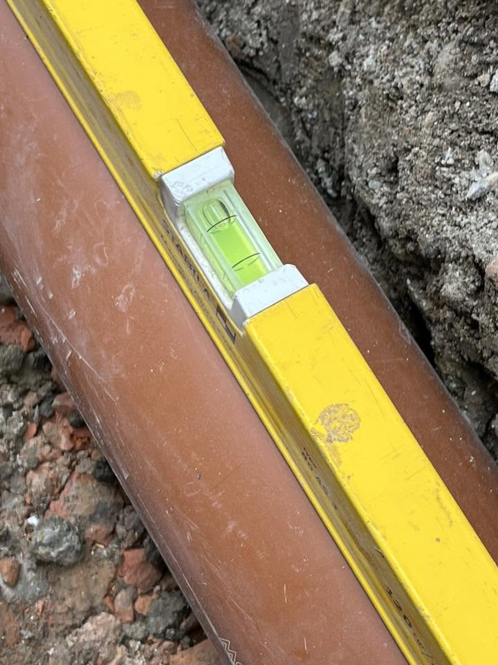 Close-up of the spirit level confirming the correct fall on the finished pipe run