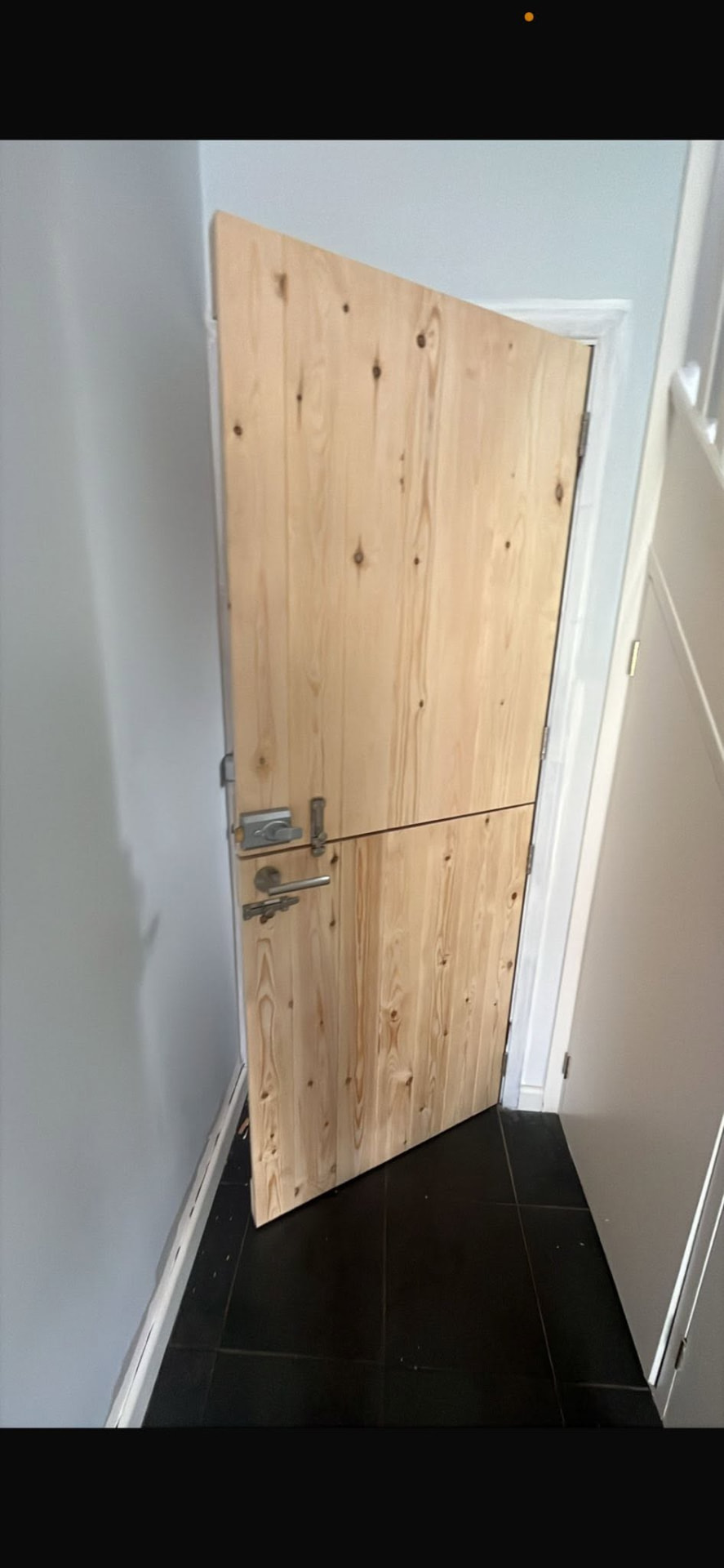 New unfinished timber door hung and being fitted
