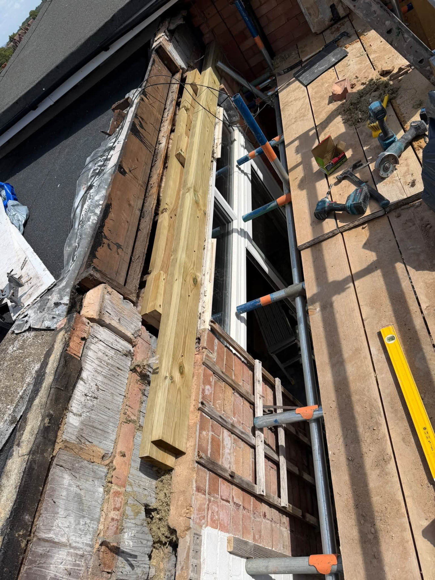 New treated timber beam fitted alongside the stripped-out roof edge above a window