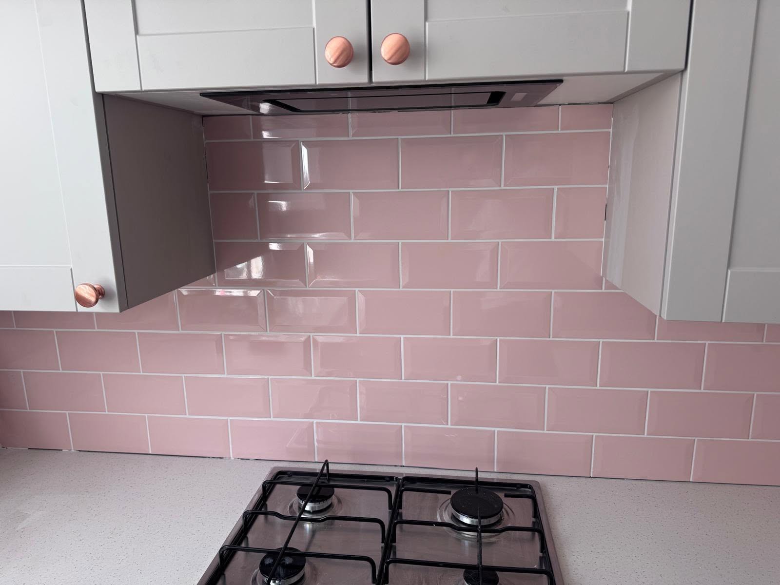 Close-up of the completed blush pink subway tile splashback above the hob